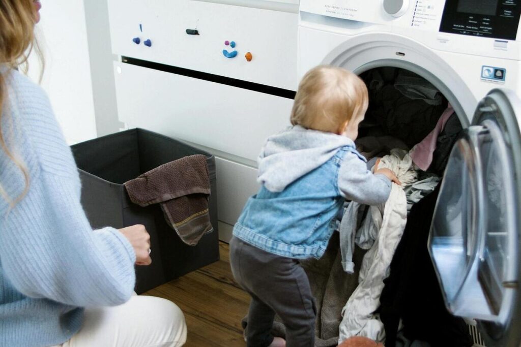 kid placing laundry into the washing machine